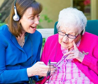 Maribeth Gallagher with patient Sue Crawford, 100, at Gardiner Home listening to music