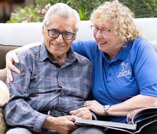 Dementia activities coordinator Gail Higginbotham, CNA, reading book to patient Feliciano Ordonez.