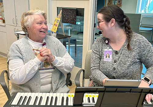 Adult Day Club member at the piano with music therapist Amanda Marcum
